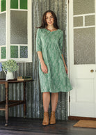 Woman wearing a 100% cotton floral dress with tan boots in a rustic room