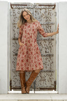 Woman wearing cotton dress in cream based floral print with one hand in pocket