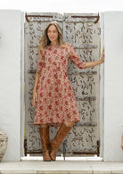 Woman wearing a 100% cotton cream based floral dress with sleeves and pockets