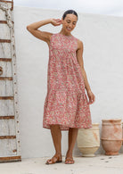Woman wears a sleeveless, relaxed fit  floral cotton dress with tiered style, empire waist and pockets.