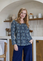 Model wearing 100% cotton long sleeve top with round neckline and tiny pleat detail from the center of the neckline.