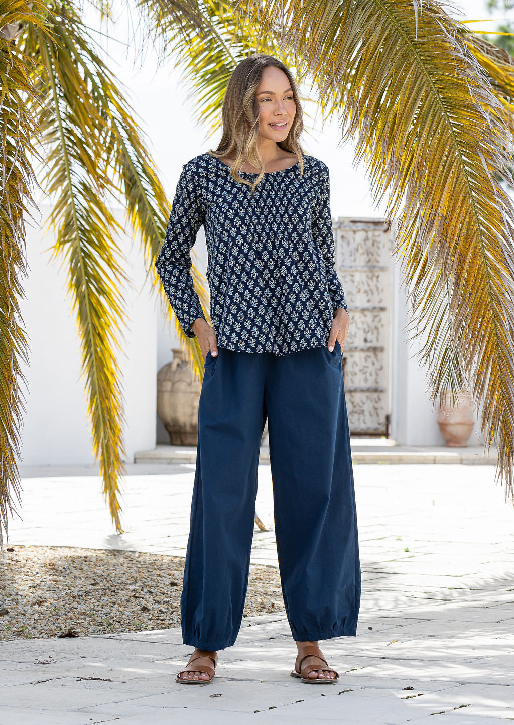 Model wearing 100% cotton long sleeve top with round neckline and tiny pleat detail from the center of the neckline.