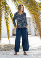 Model wearing 100% cotton long sleeve top with round neckline and tiny pleat detail from the center of the neckline.