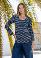 Woman wearing a 100% cotton navy floral top and blue pants standing in front of palm trees.