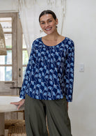 Model wearing 100% cotton long sleeve top with round neckline and tiny pleat detail from the center of the neckline.