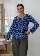 Model wearing a flattering long sleeve top with navy blue based florals with plain pants.