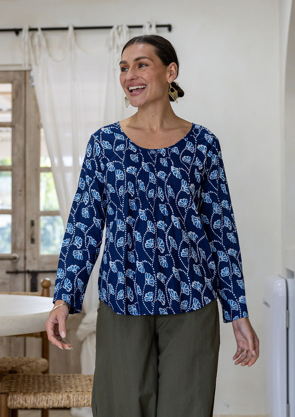 Woman wearing a 100% cotton long sleeve top in navy blue based floral print with round neckline.