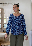 Woman wearing a 100% cotton long sleeve top in navy blue based floral print with round neckline.