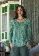 Model wearing 100% cotton long sleeve top with round neckline and tiny pleat detail from the center of the neckline.