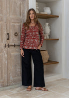 Model wearing a flattering long sleeve top with beautiful red based florals with plain black pants.