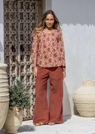 Model wearing 100% cotton long sleeve top with round neckline and tiny pleat detail from the center of the neckline.