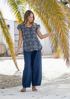 Woman wearing a navy blue based floral print short sleeve top with scoop round neckline and pleated detail across the bodice