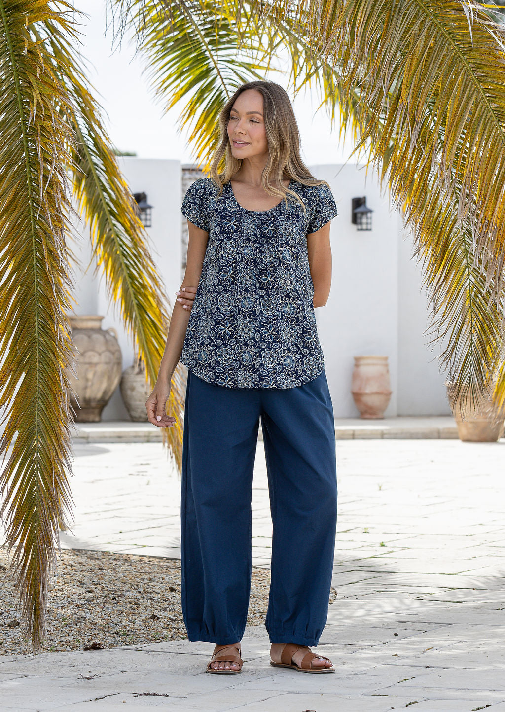Woman wearing 100 percent cotton top with short cap sleeves and longer back hem.