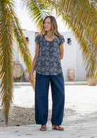 Woman wearing 100 percent cotton top with short cap sleeves and longer back hem.