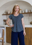 Woman wearing a blue floral top and plain pants in a kitchen setting