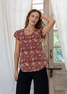 Woman wearing 100 percent cotton top with short cap sleeves and longer back hem.