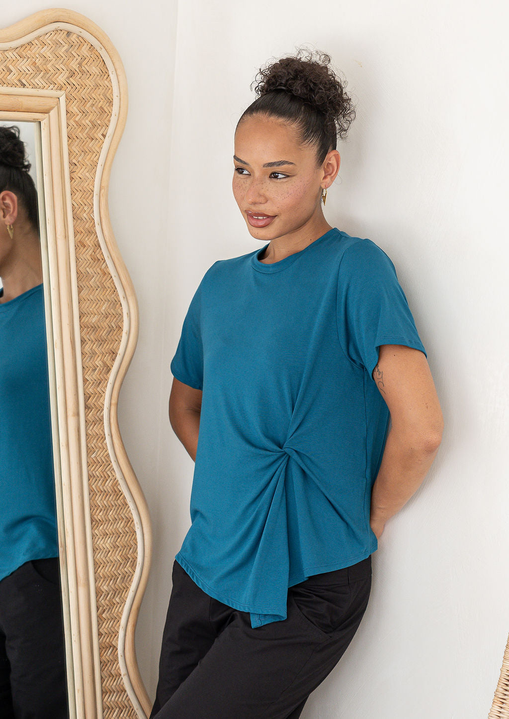 Woman wearing teal crew-neck T-shirt with twist knot front, stretch rayon jersey short-sleeve top