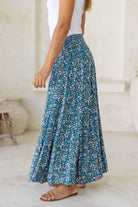 Close up of a model wearing a blue based flowy, wide legged pants with smocked elastic waistband.