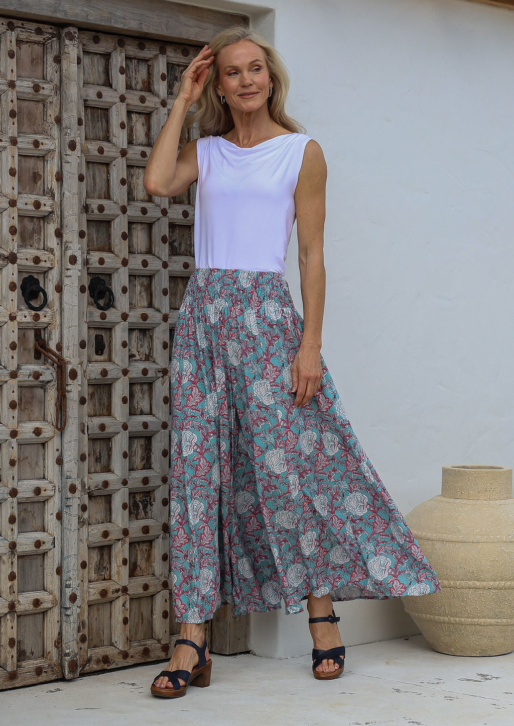 Woman posing in wide leg floral print palazzo pants with a smocked elastic waistband.