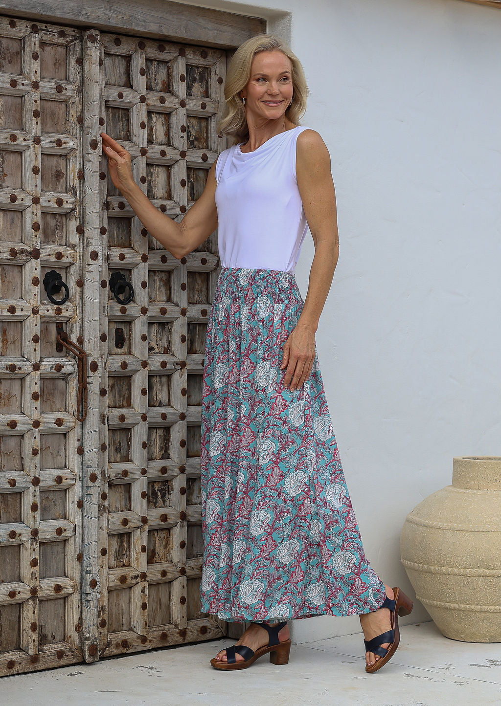 Woman wears 100% rayon super wideleg floral pants in a soft blue shade, paired with a basic white singlet.