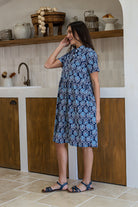 Woman wearing a 100% cotton relaxed fit collared short sleeve dress with hidden side pockets. 