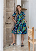 Woman wearing a 100% cotton relaxed fit collared short sleeve dress with hand in pockets.