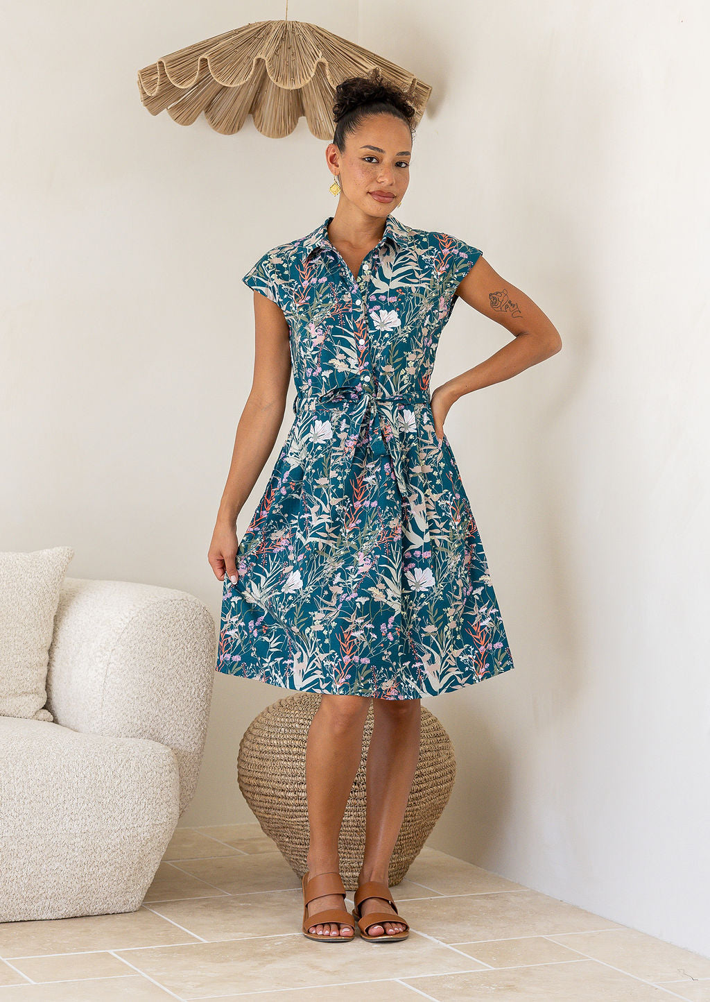 Woman wearing the Ursula Dress in Verdure, a teal cotton shirt dress with wildflower print fit and flare style 