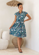 Woman wearing a floral dress standing in a room with a neutral color scheme.