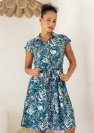 Woman wearing the Ursula Dress in Verdure, a teal cotton shirt dress with wildflower print