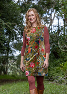Woman wearing a velvet cotton floral tunic with a basic terracotta top and brown boots standing in a natural setting.