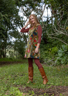 Woman in a cotton velvet floral dress and brown boots standing in a forest