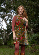 Woman wearing a floral tunic standing outdoors with greenery in the background