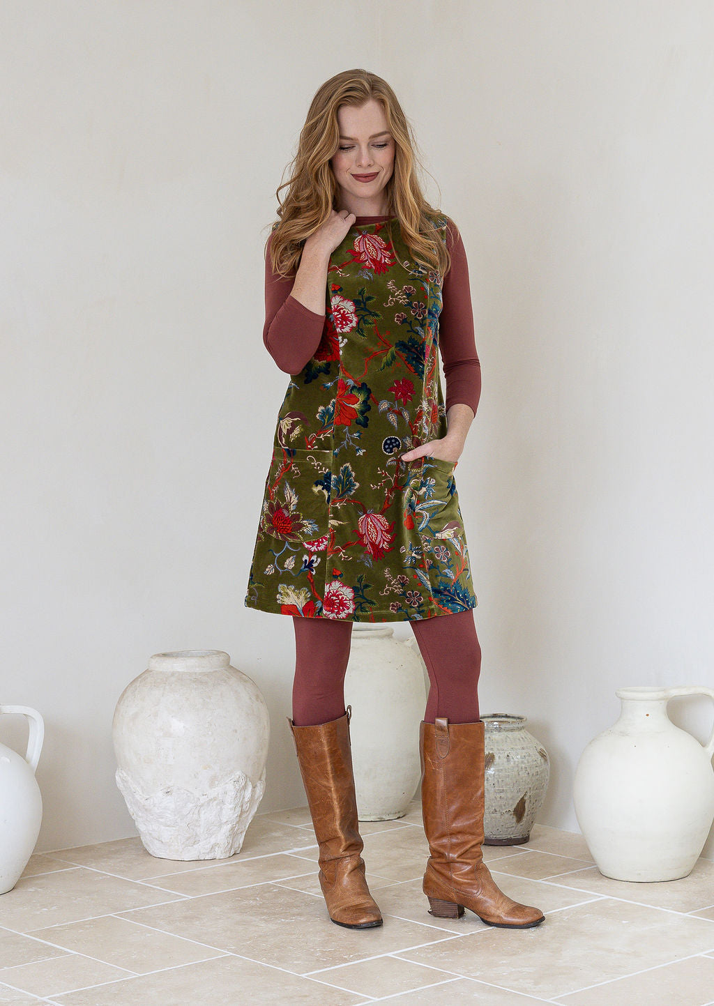 Woman wearing a moss green based multi-coloured floral print cotton velvet sleeveless tunic with pockets and side zip