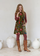 Woman wearing a moss green based multi-coloured floral print cotton velvet sleeveless tunic with pockets and side zip