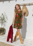 Woman in a floral cotton velvet tunic and brown boots standing in a kitchen.