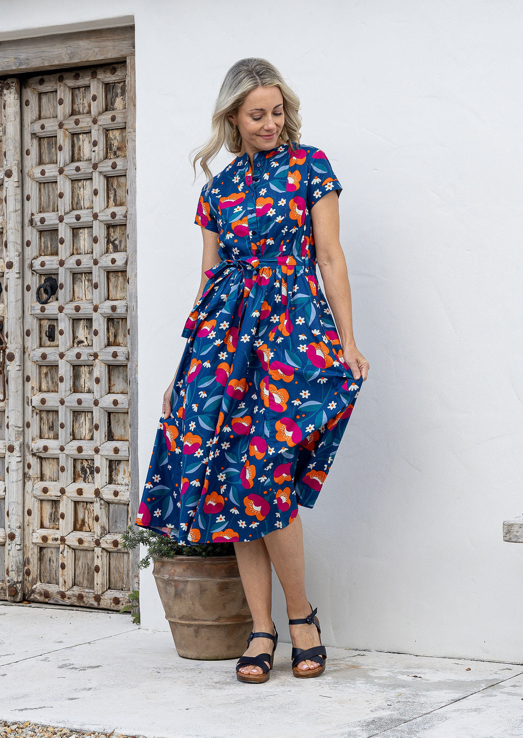 Woman wearing a 1950's style short sleeved, button through cotton dress and high round neckline with pockets