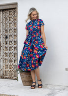Woman wearing a 1950's style short sleeved, button through cotton dress and high round neckline with pockets