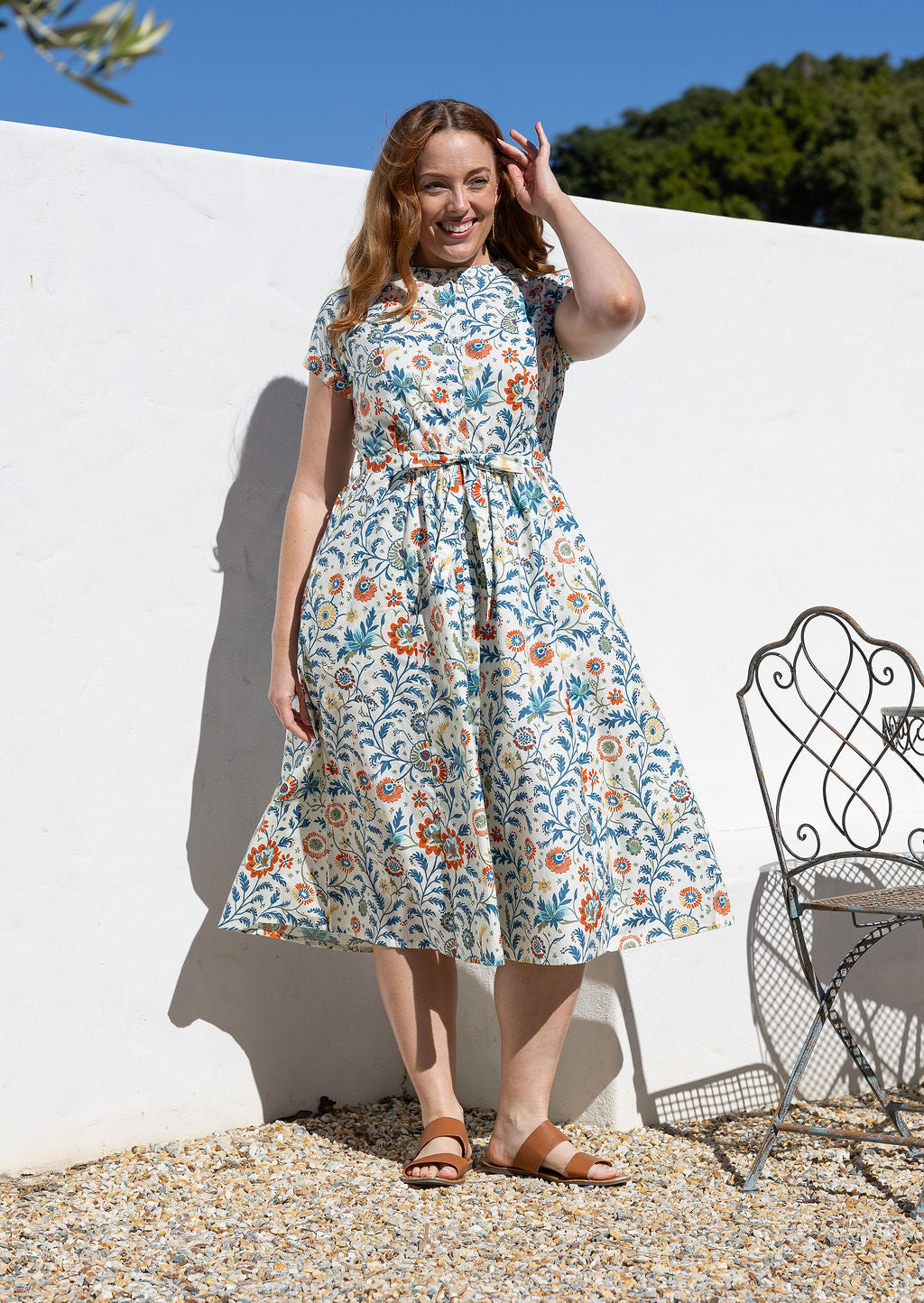 Woman wearing a 1950's style short sleeved, button through cotton dress and high round neckline with pockets