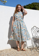 Woman wearing a 1950's style short sleeved, button through cotton dress and high round neckline with pockets
