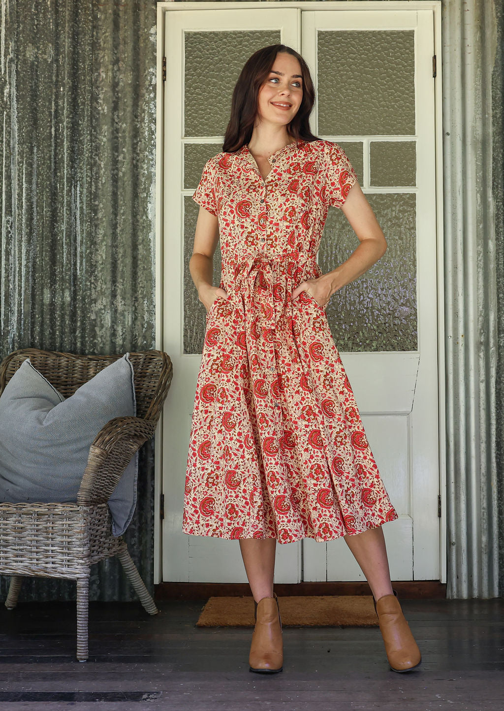 Woman wearing a 1950's style short sleeved, button through cotton dress and high round neckline with hands in pockets