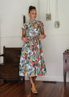 Woman wearing a 1950's style short sleeved, button through cotton dress and high round neckline with hands in pocket