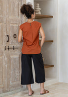 Woman wearing 100% cotton top in orange brushetta colour with subtle keyhole and button closure at the back