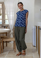 Woman wears 100% cotton top in navy based floral print with cap sleeves paired with plain pants