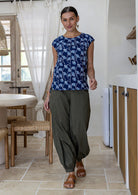 Woman wearing a navy based floral cotton top and plain pants standing in modern kitchen interior.