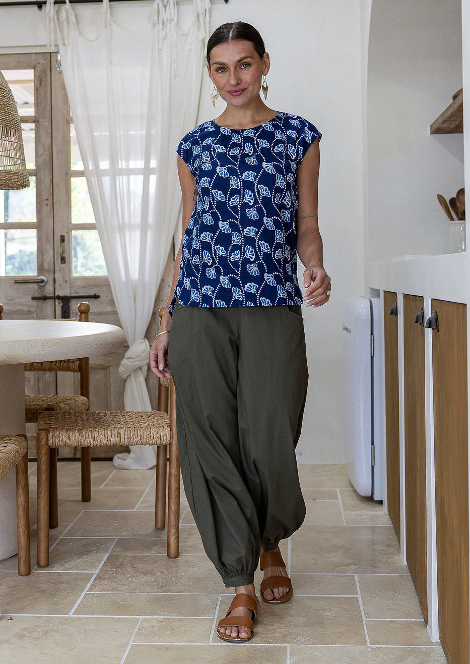 Woman wearing a navy based floral cotton top and plain pants standing in modern kitchen interior.