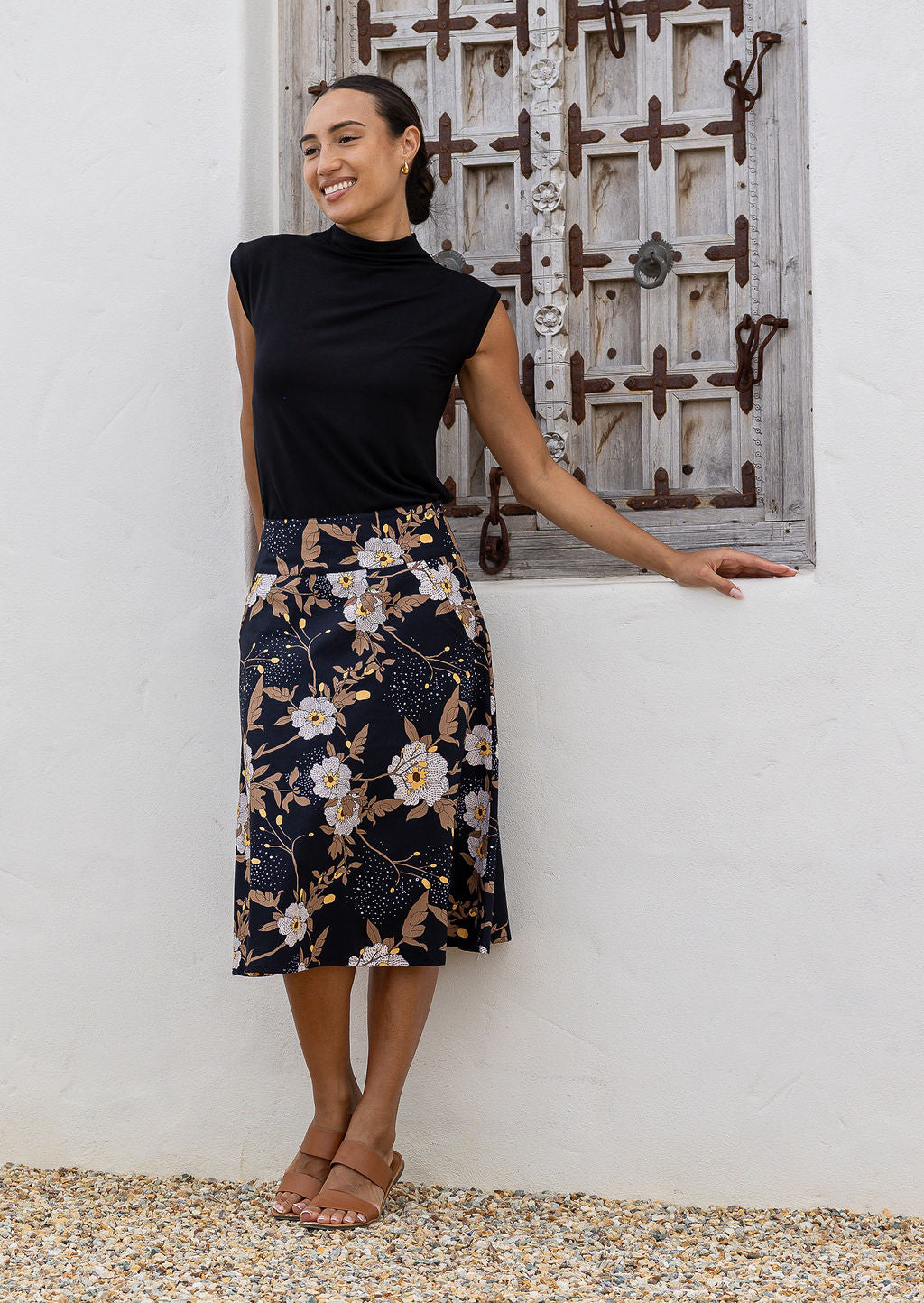Woman wearing a basic black top and black floral a-line cotton skirt with side zipper 