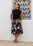 Model wearing 100% cotton knee length A-line skirt with side zipper and pockets in black based floral print