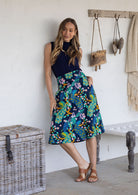 Woman is posing with one hand in pocket wearing a 100% cotton navy based floral print a line skirt.