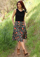 Model wears 100% cotton generous A-line skirt that sits over the knee with her hands in pockets on hips