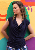 Woman wearing a cowl neck rayon navy blue cap sleeve top.